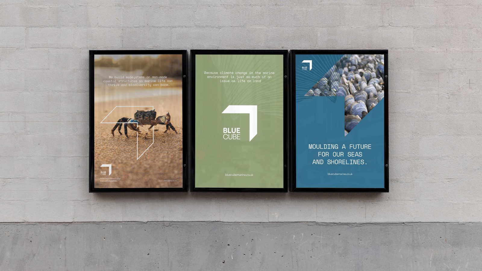 Three framed posters mounted on a concrete wall, each promoting environmental sustainability with images of a robotic device on arid land, a geometric blue cube, and hands holding earth designed by a Brand Agency UK.