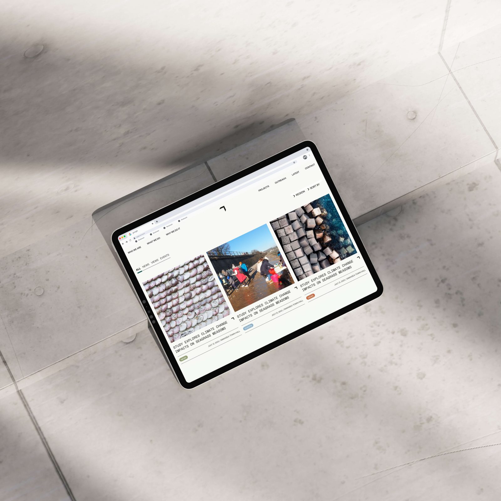 A tablet displaying a social media page with multiple images on its screen, lying on a light-toned marble surface. The images on the tablet, curated by a leading Design Agency in Bristol, show outdoor