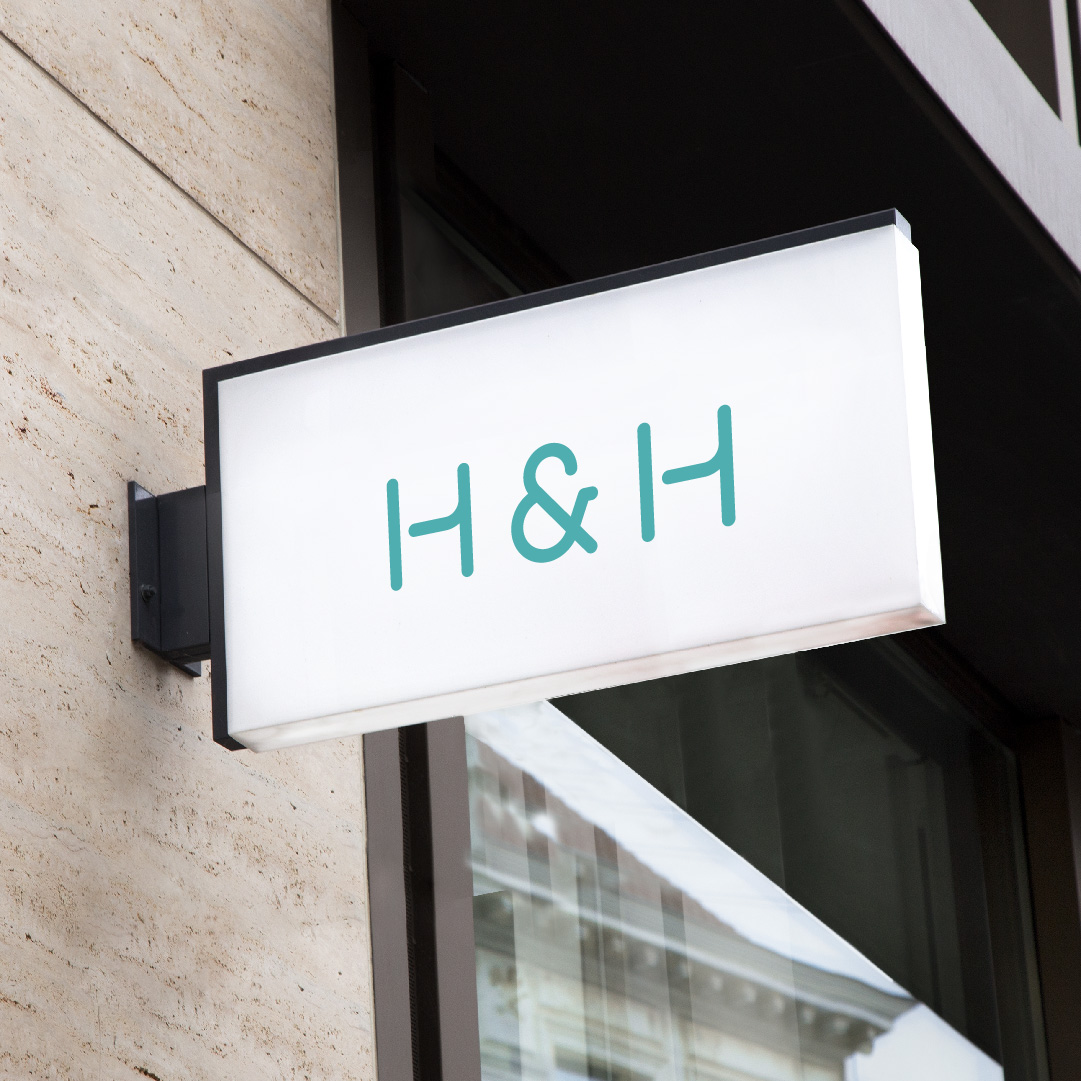 A white rectangular sign mounted on a building facade displaying the green letters 