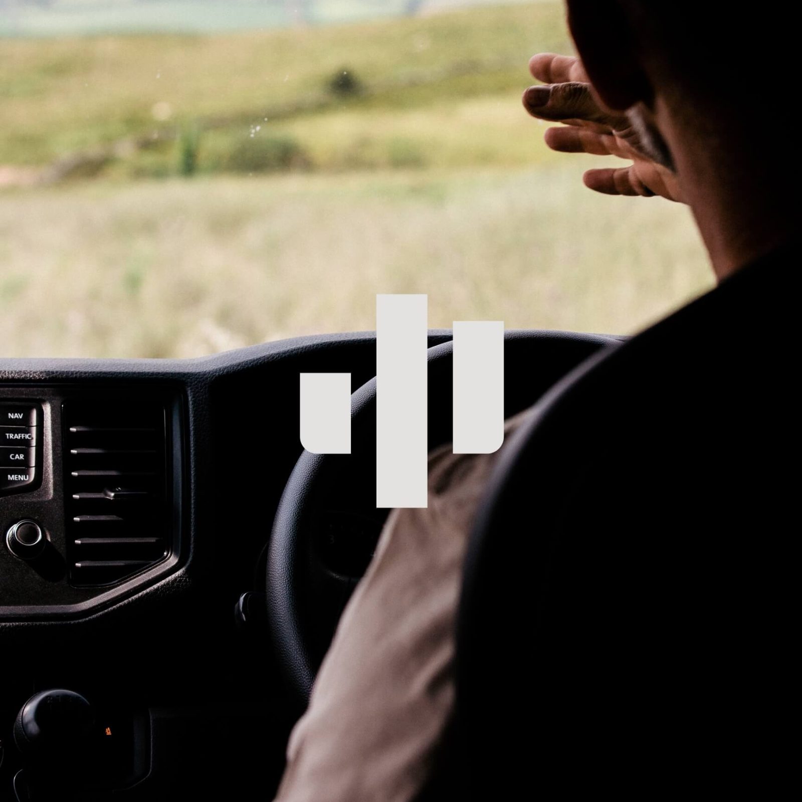 The image shows the back view of a person driving a car, looking out at a scenic landscape through the windshield.
