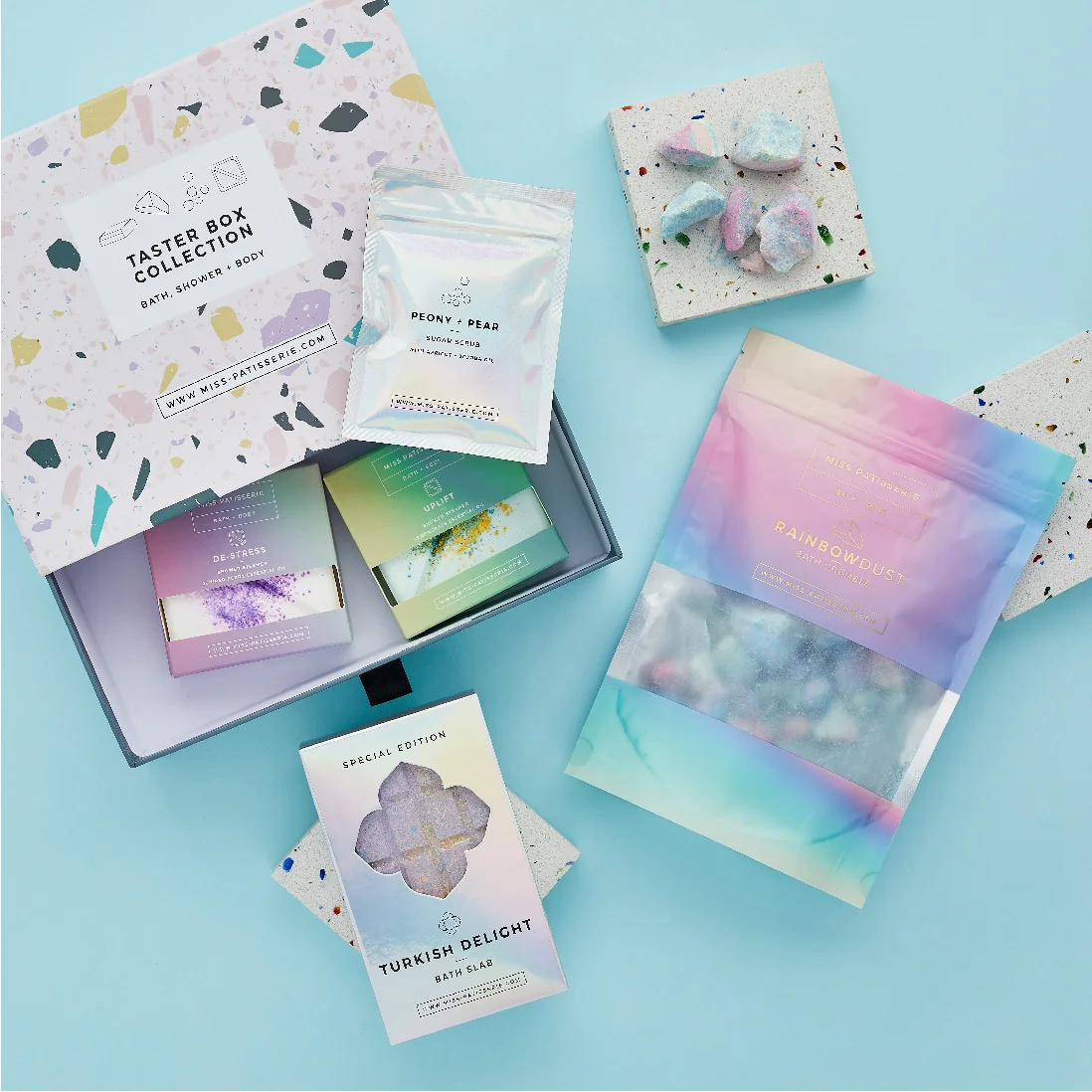 An assortment of colorful bath products displayed on a website designed by a top design agency in Wales, including pouches labeled 'rainbow dust' and 'pony pop', and bars of soap decorated with