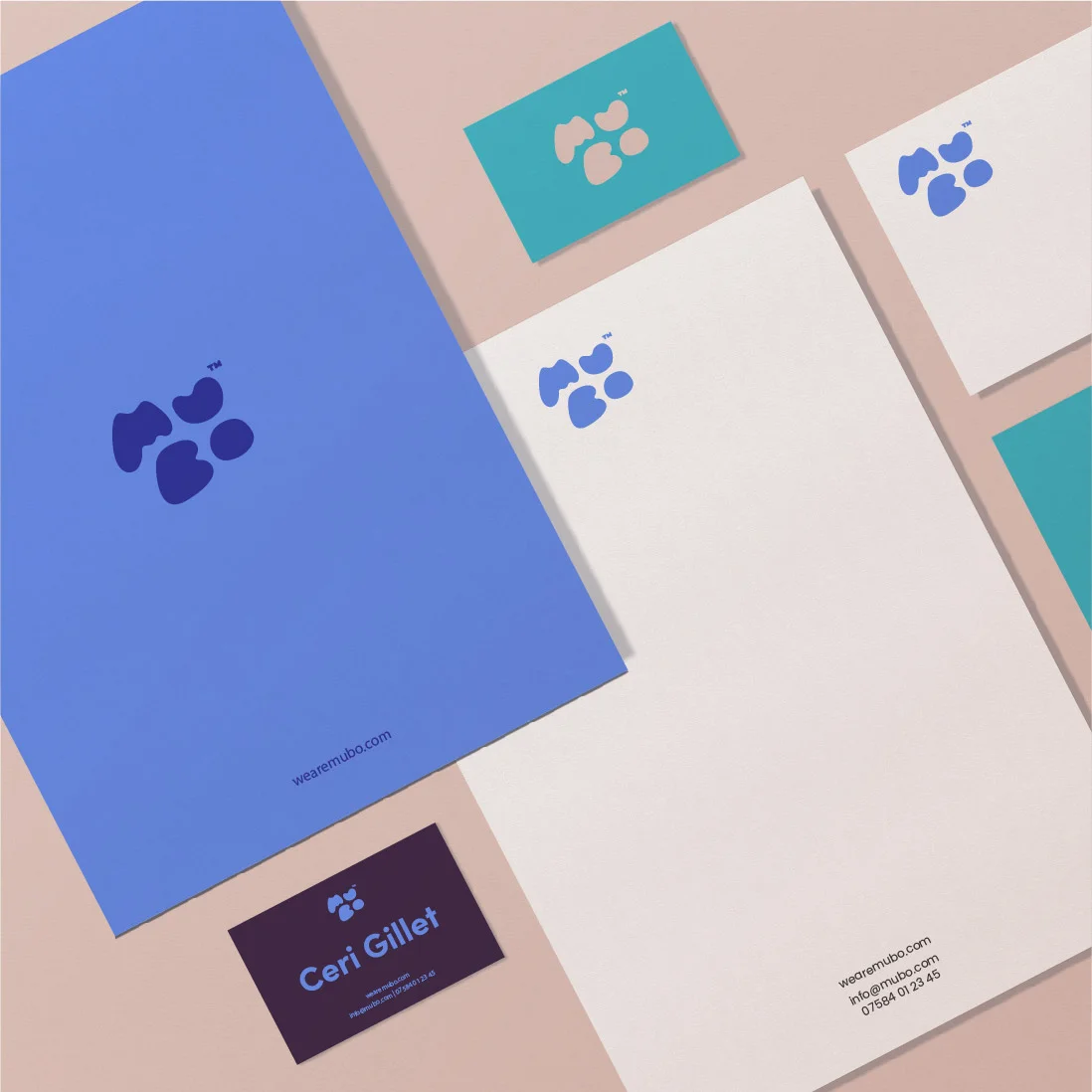 A flat lay of brand design materials in blue and white, including business cards, letterheads, and envelopes, each featuring a paw print logo.