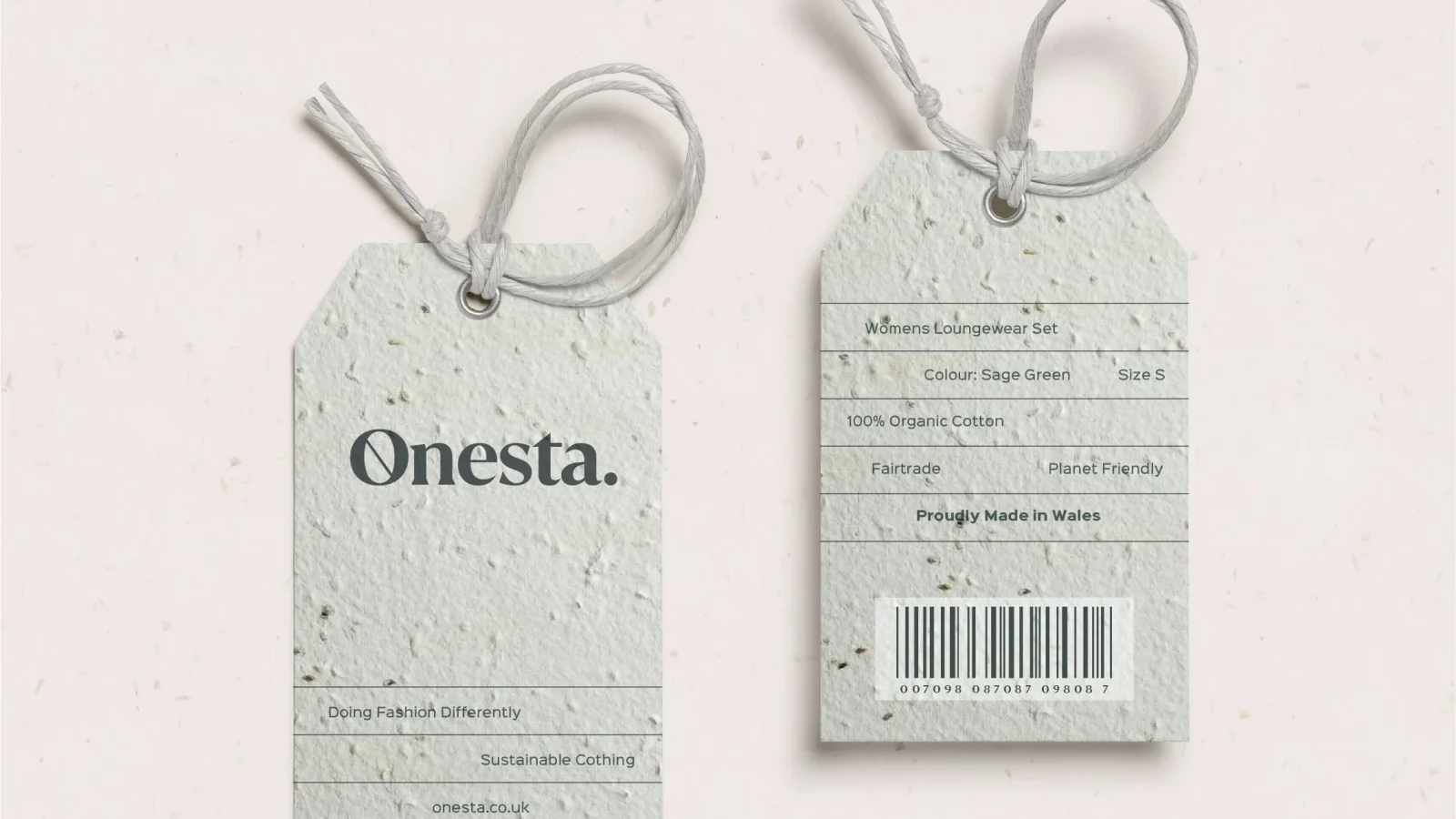 Two clothing tags designed by a design agency in Wales for the Onesta brand on a speckled paper background. One shows the front with the brand logo, and the other displays sizing, material information
