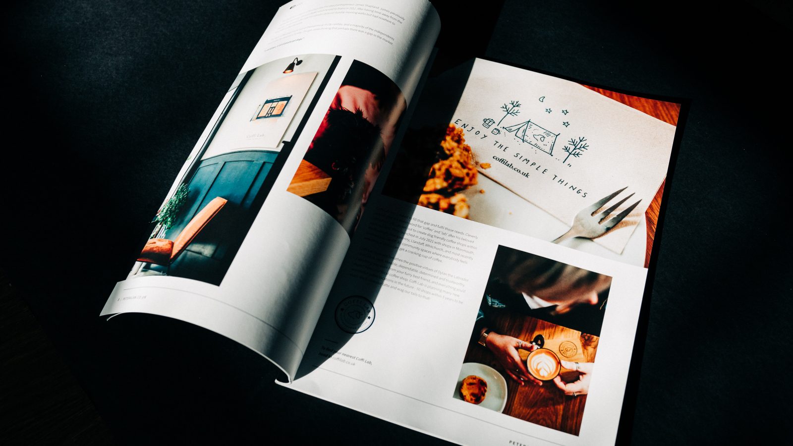 An open magazine on a dark table featuring a well-designed, full-page food article with vibrant photographs of dishes and a graphic design recipe layout. Light illuminates the pages from the top.
