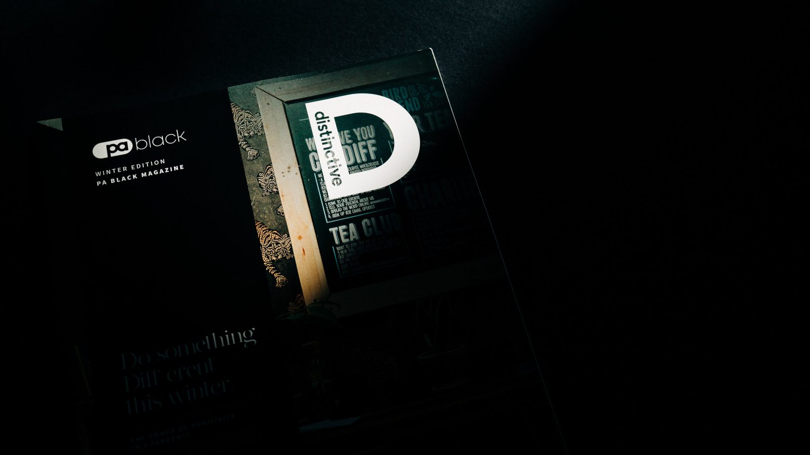 A magazine partially illuminated by sunlight with a visible page that shows an advertisement featuring the text 