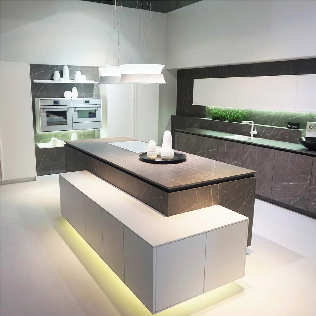 Modern kitchen design featuring sleek surfaces, an island with a waterfall countertop, built-in appliances, and hanging pendant lights with a soft, ambient glow crafted by a leading Design Agency UK.