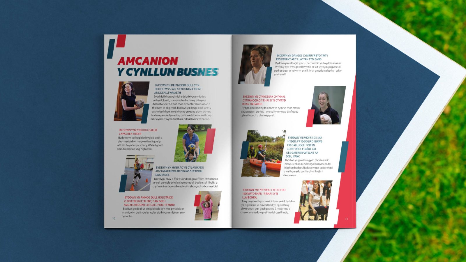 An open brochure on grass, featuring multiple pages with text and images of people engaging in various professional activities, highlighted by bold red and white design elements from Design Agency Bristol.