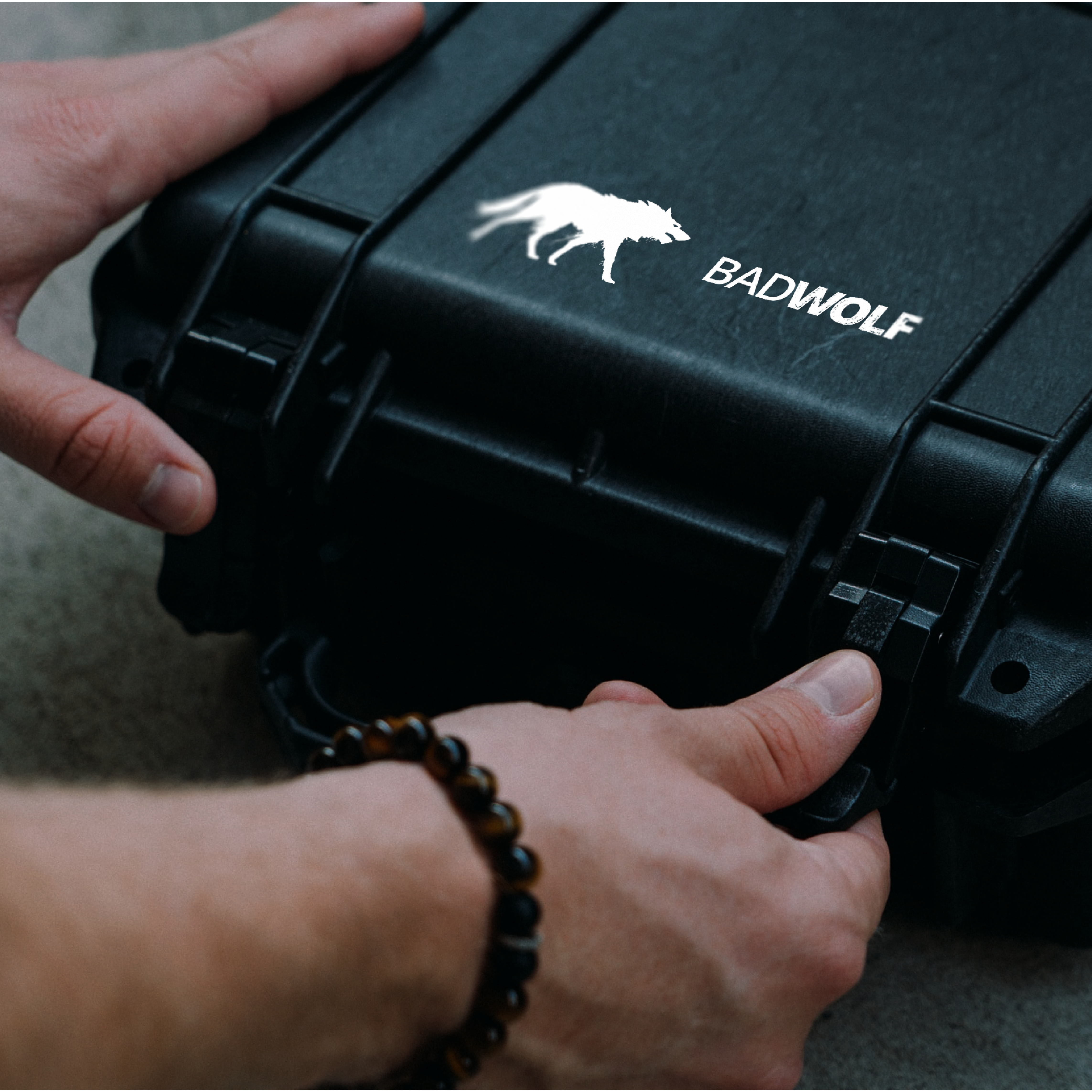 A person holds a closed black protective case with a white logo of a wolf and the word 
