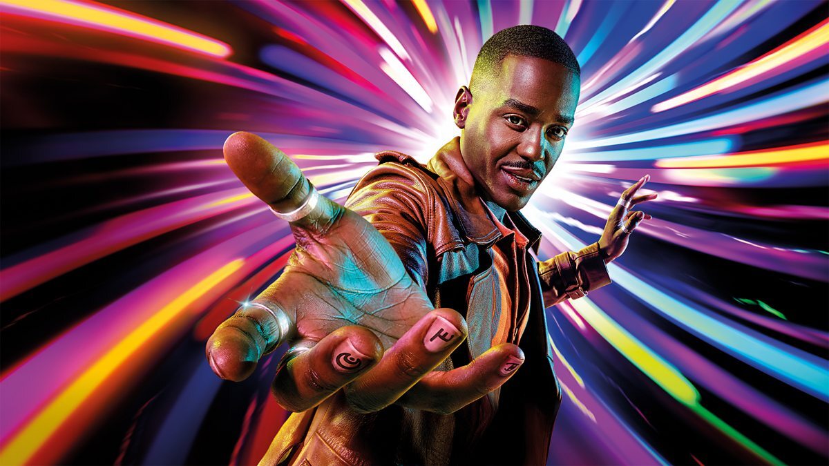 A man extends his hand toward the camera, wearing a futuristic glove designed by a Brand Agency Cardiff, against a dynamic, colorful light trail background, conveying a sense of motion and energy.