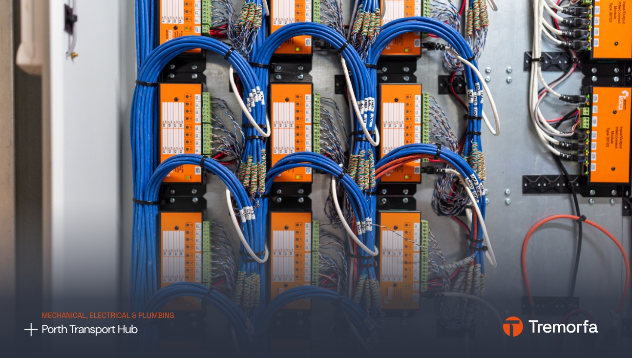A neatly organized electrical panel with blue and orange cables connected to multiple switches and circuit breakers, labeled for easy identification by a design agency, in an industrial setting.