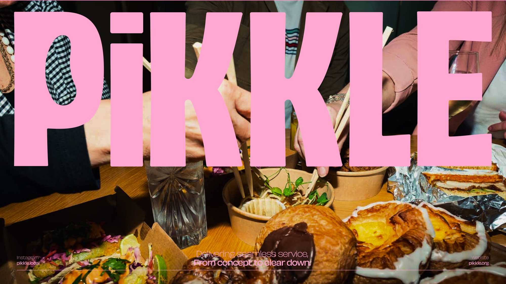 People enjoying a meal with dishes on a wooden table, while the word 