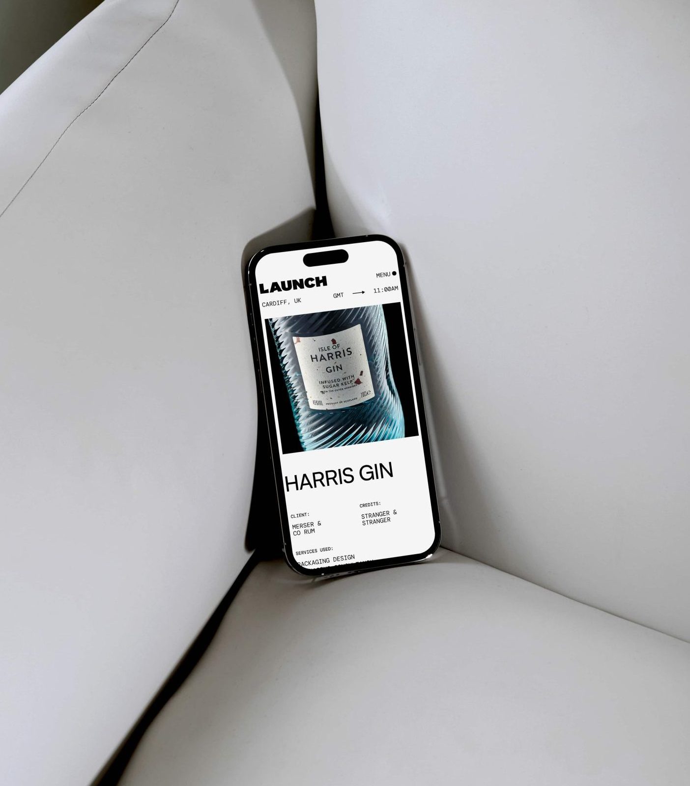 Smartphone resting on white cushions displays a website featuring Harris Gin on the screen, with 'bad wolf' subtly etched in the background design.