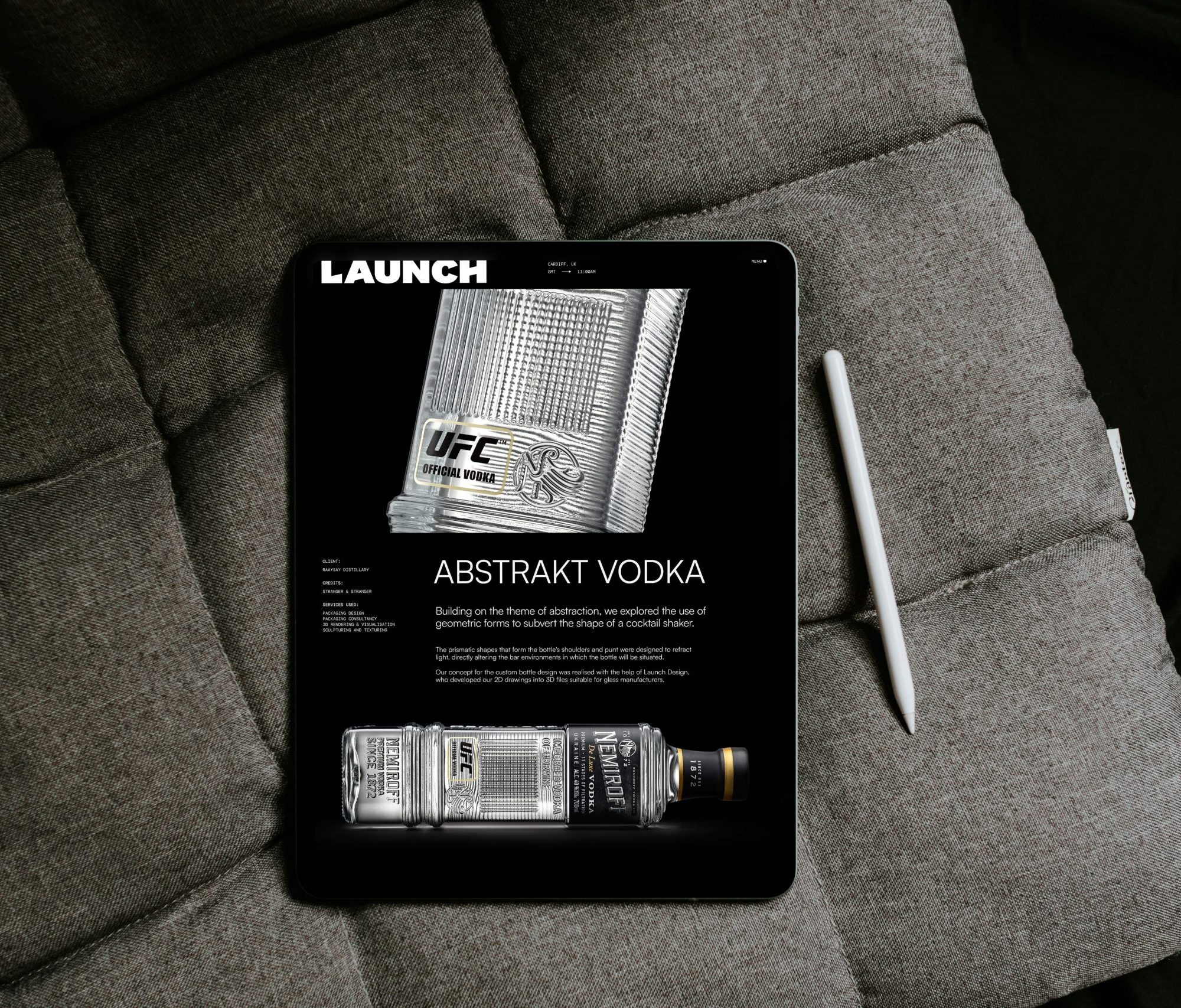 A tablet displaying an Abstrakt Vodka advertisement sits on a gray cushioned surface, with a stylus resting beside it, evoking the intrigue of a cunning bad wolf lurking in the shadows.