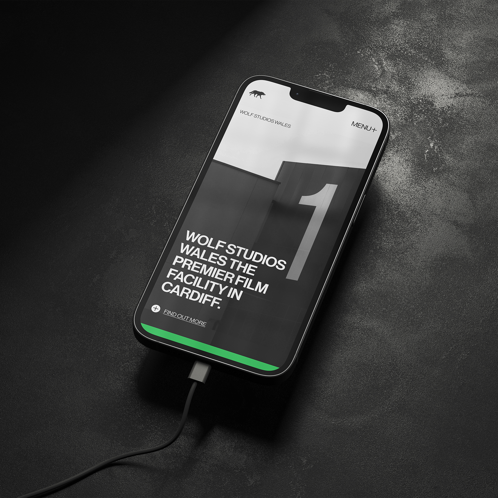 Designdough-Badwolf-studio-CTA-flex A smartphone on a dark surface displays a webpage for Wolf Studios Wales, a film facility in Cardiff.